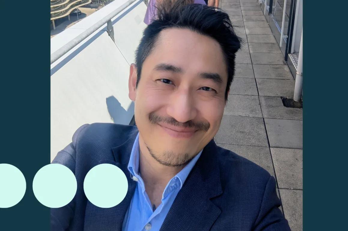 Selfie taken by Asian man, smiling and wearing a suit 