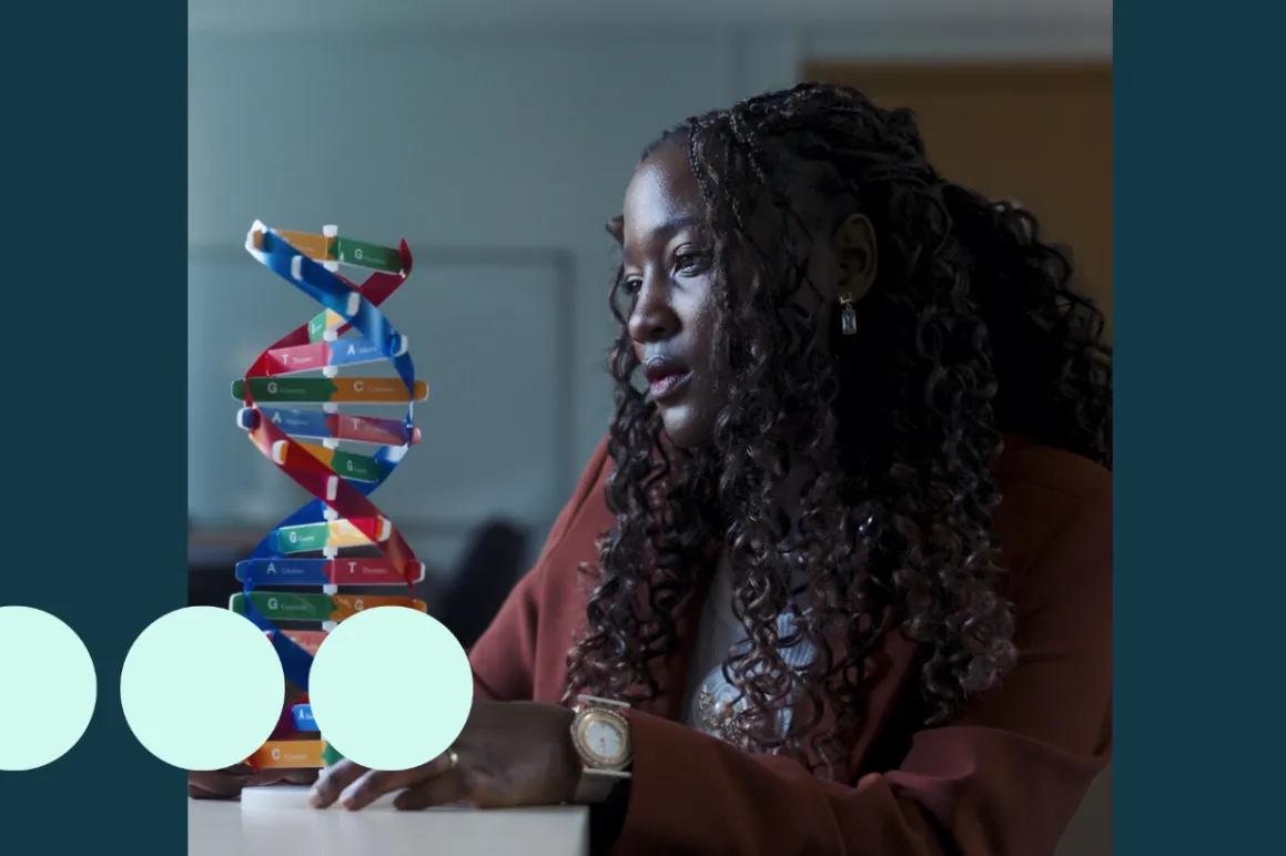 Black woman, sat analysing a DNA model 
