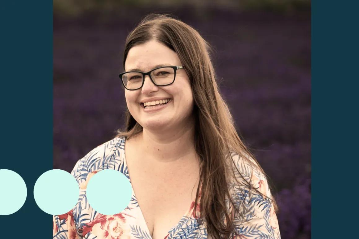 woman with long brown hair and glasses smiling for photo 