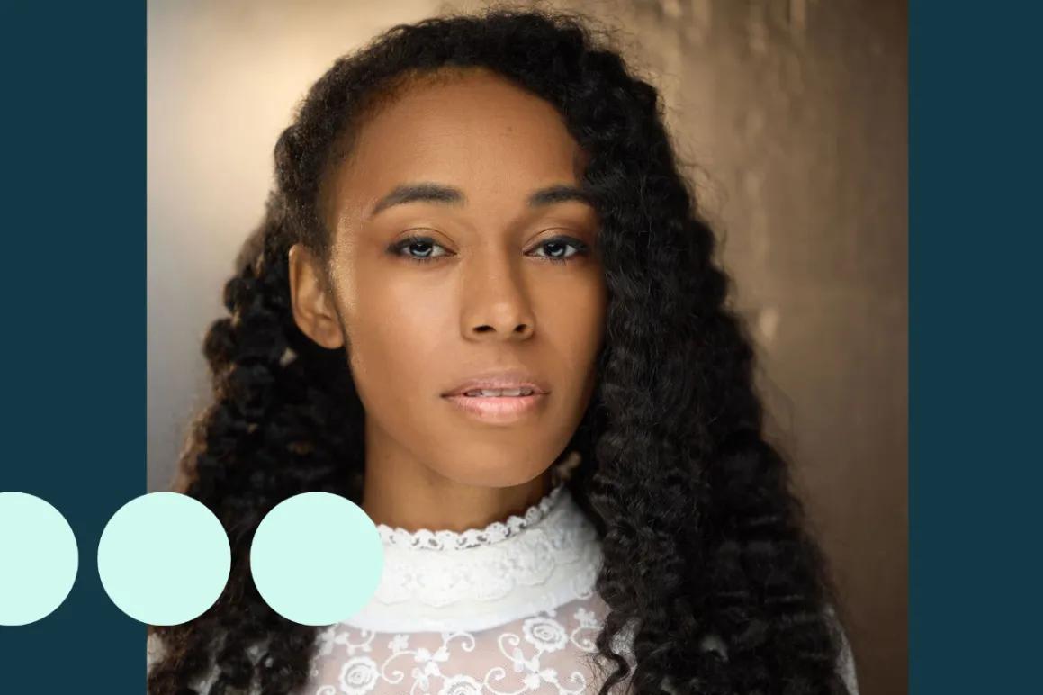 Headshot of woman with thick black curly hair, looking directly into camera