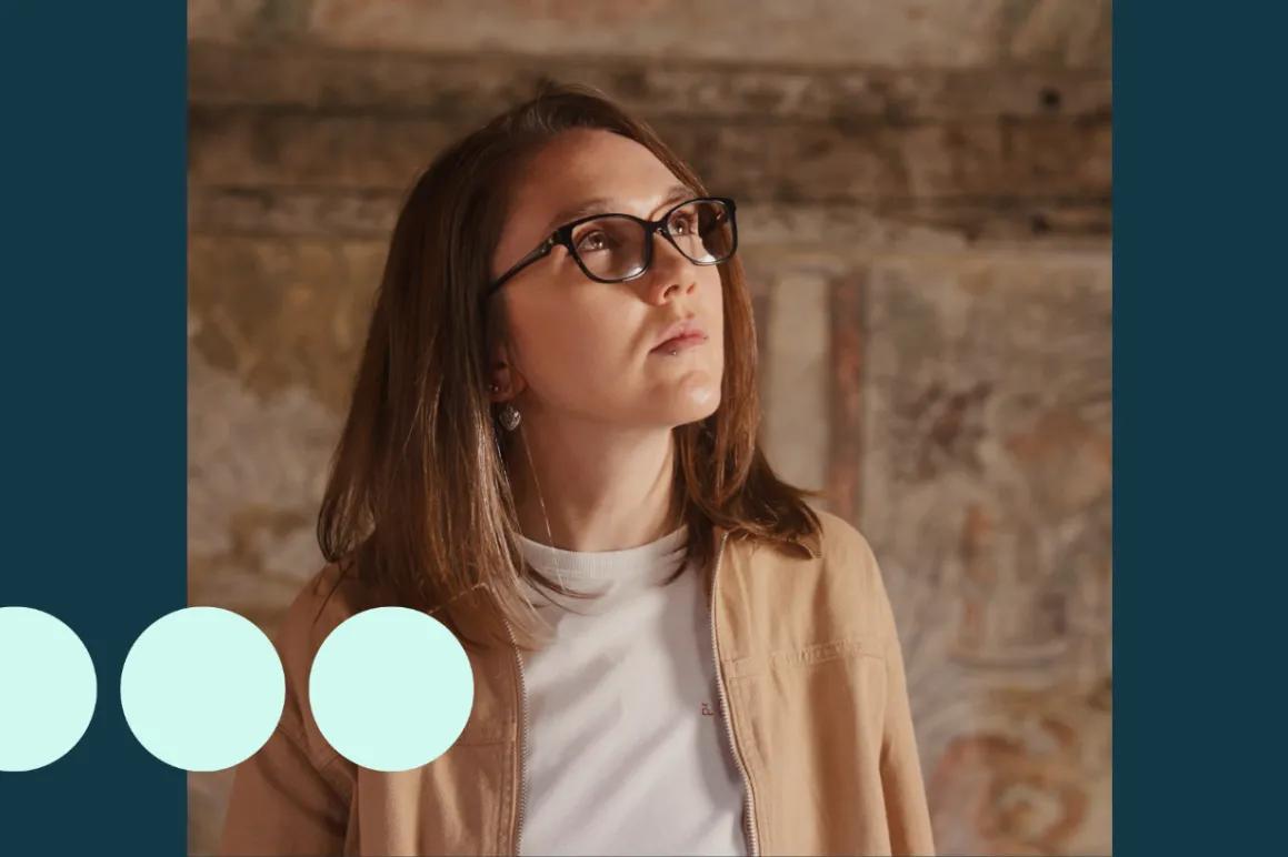 Woman with glasses looking up at tapestry 