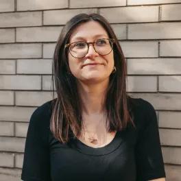 Woman looking slightly off camera stood against a wall